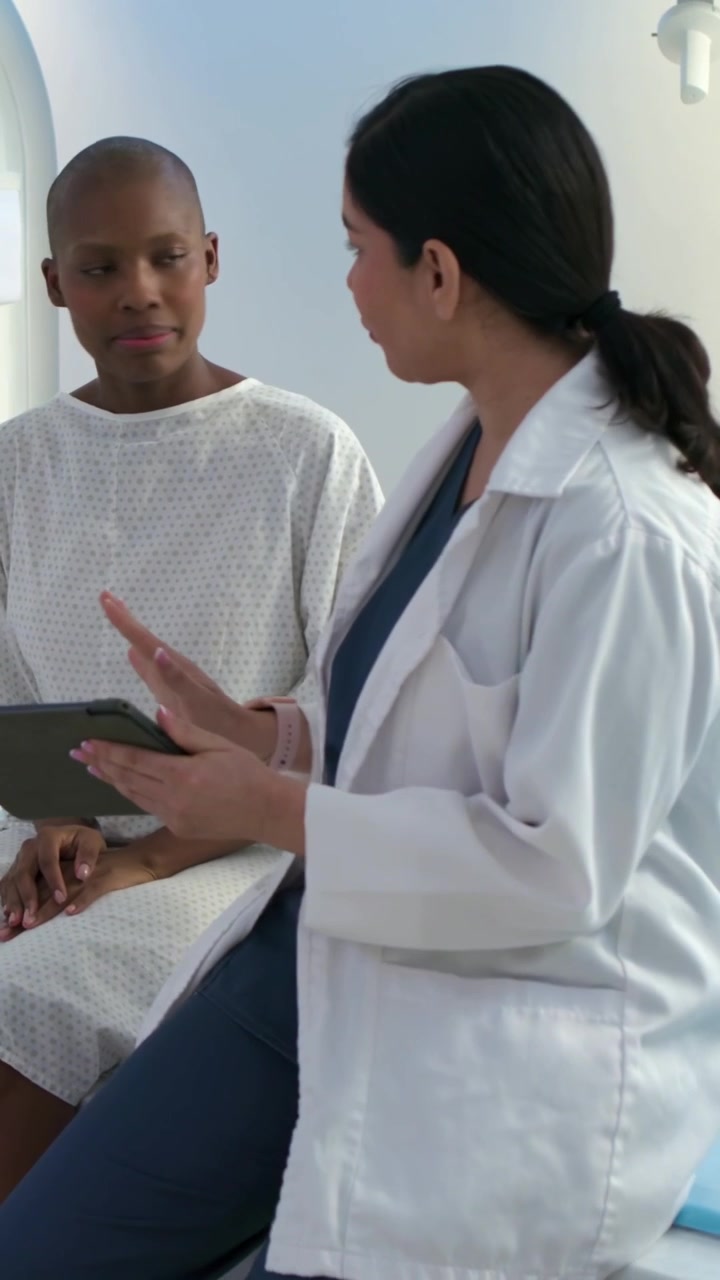 Vertical video: Walking clinician in lab coat preparing gowned patient for MRI by scanner on tablet
