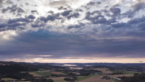 nubes oscuras y melancólicas que se arremolinan sobre el mosaico de los campos de cultivo y los pastos