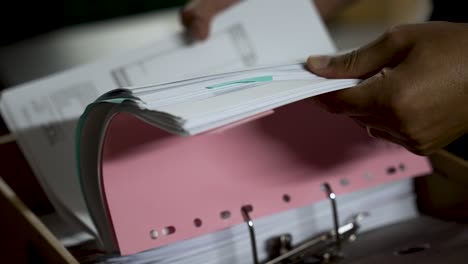 una persona filtra una carpeta de documentos, organizando varios papeles de contabilidad, facturas y archivos de oficina