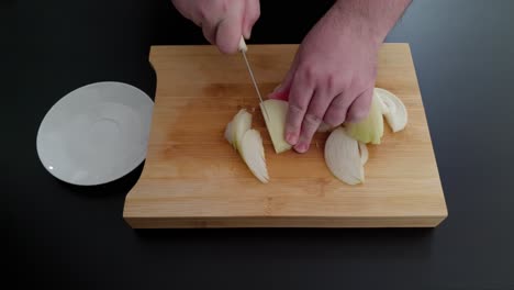 person cutting white onion on wooden chopping board with saucer on the side