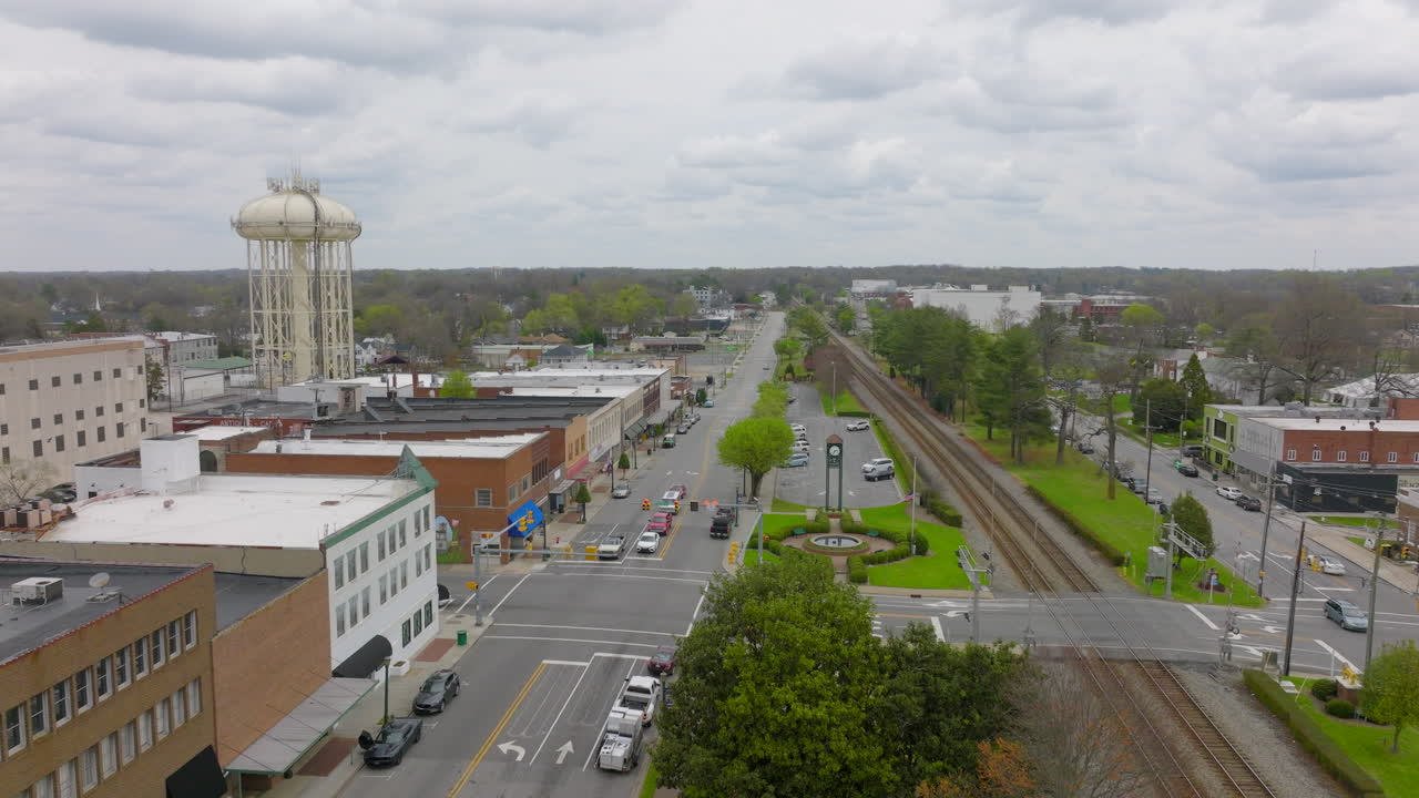boom aereo sopra il centro di thomasville, carolina del nord sopra la strada principale con vetrine di negozi e binari del treno e una torre dell'acqua