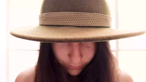 portrait of attractive woman in hat looking into camera 4k. girl with big eyes peeps out the hat and looks into the camera