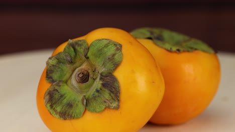 two persimmons resting on a table