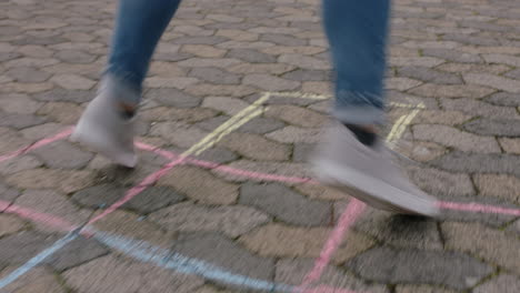 cerca de una adolescente jugando al juego de hopscotch saltando en cuadrados coloridos en el patio de recreo de la escuela divirtiéndose al aire libre