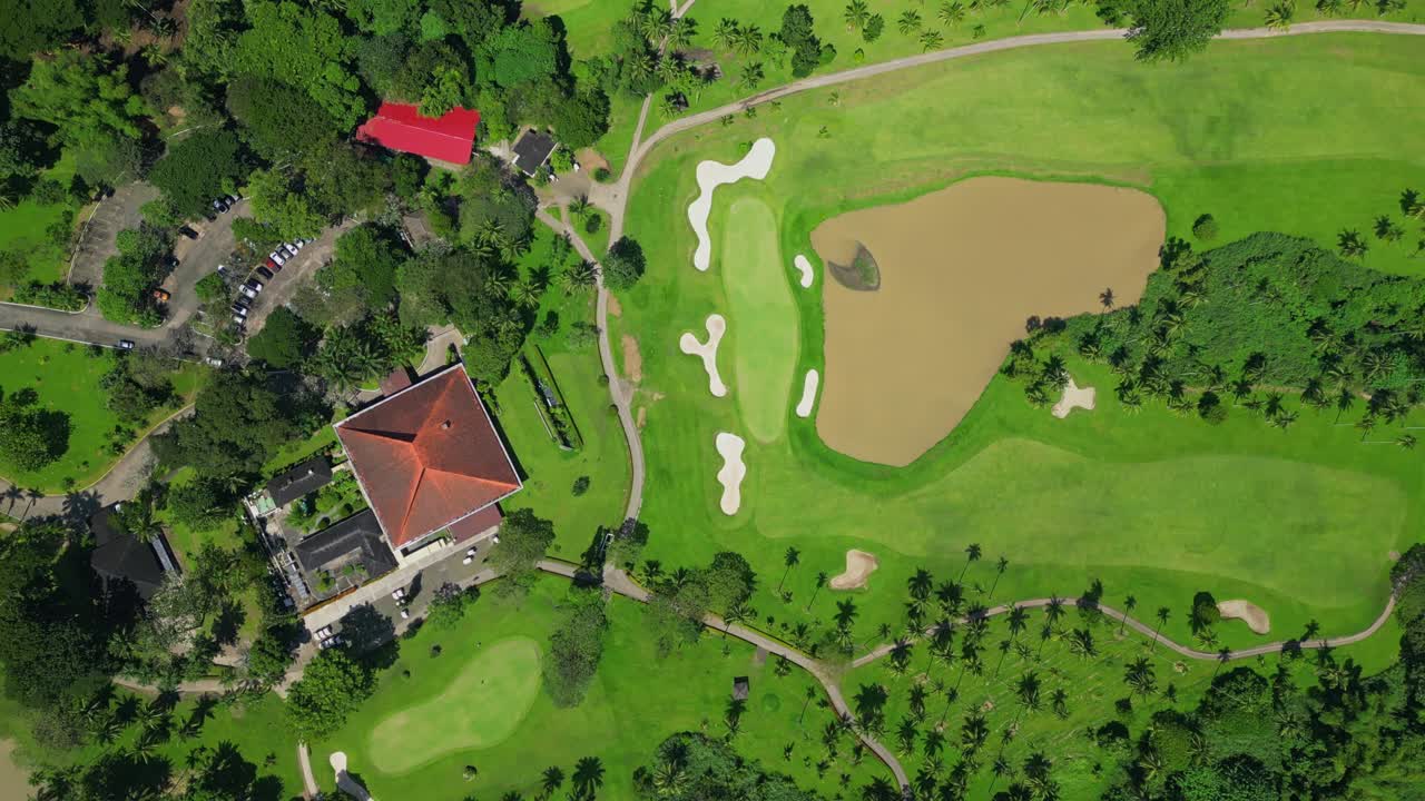 A circling downward top view aerial showcasing the expansive grounds of Canlubang Golf and Country Club, showing manicured fairways, water puddles, and tropical greenery in Calamba Laguna, Philippines