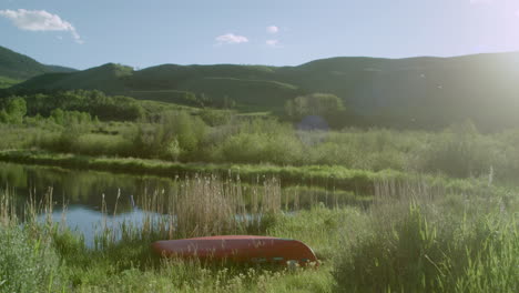 canoe boat scenic landscape of pond lake with rolling green hills mountains backdrop
