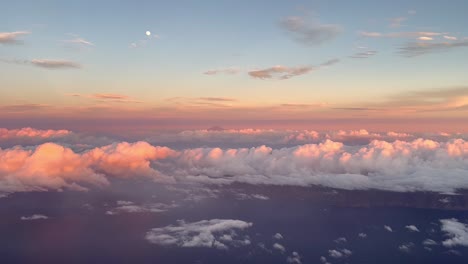 side view from the cabin of a commercial plane in flight at sunset flying over the clouds