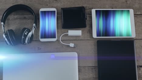 animation of light trails over technological devices with colorful moving shapes on screen on desk