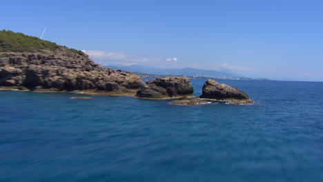 Low-aerial-revealing-shot-of-the-beach-resorts-at-Turkey-from-behind-an-island