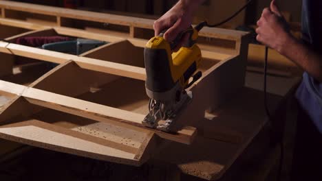 man using a jigsaw to cut wood for furniture making