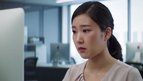 a woman is deeply engaged in her tasks at a contemporary office. she appears concentrated while looking at her screen, surrounded by a corporate environment during working hours.