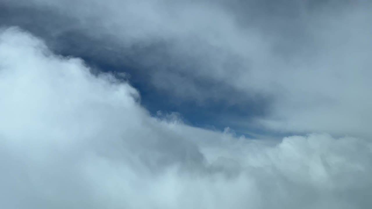 Vista dalla cabina di pilotaggio di un cielo nuvoloso che vola verso uno squarcio blu