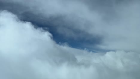 Cockpit-view-of-a-cloudy-sky-flying-toward-a-blue-gap