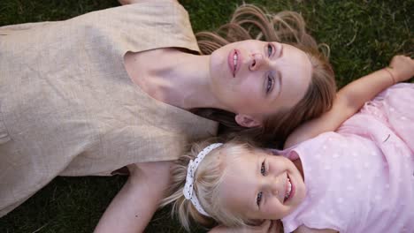 Joven-Mujer-Rubia-Agraciada-Con-Su-Pequeña-Hija-Rubia,-Relajándose-En-El-Césped-En-El-Parque-1