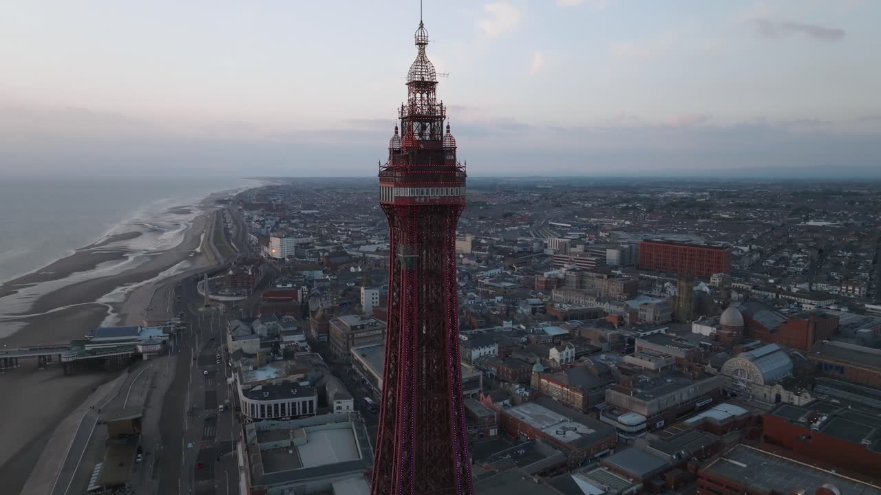 Flying towards Blackpool Tower with town behind and North pier to the left at sunset. Lancashire, UK.