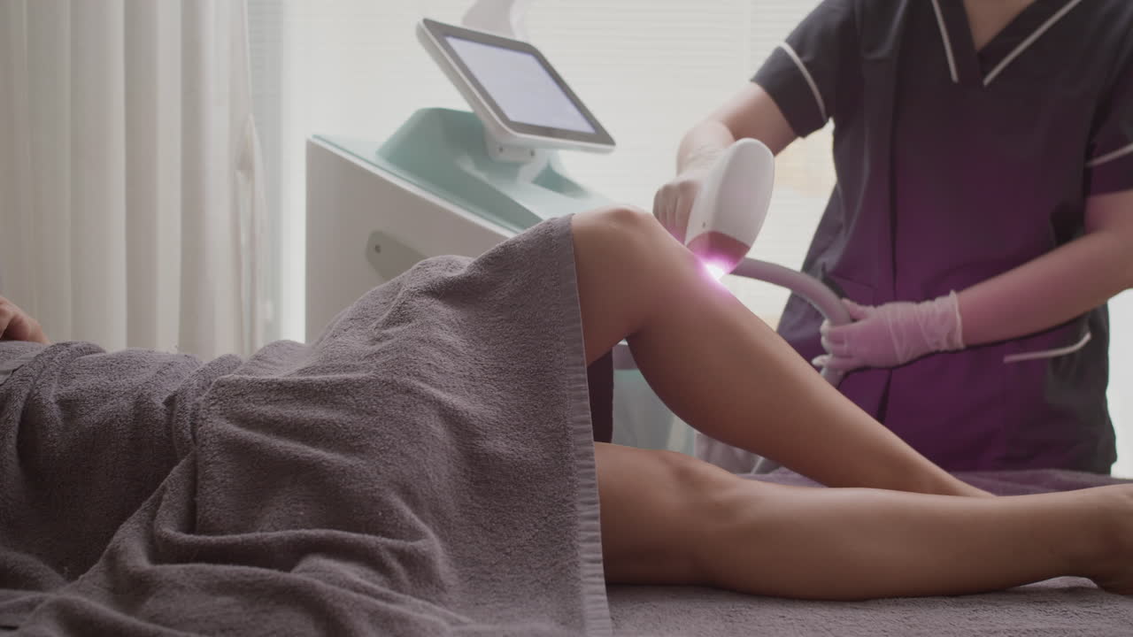 Beautician Using IPV Epilator on Legs of Female Client