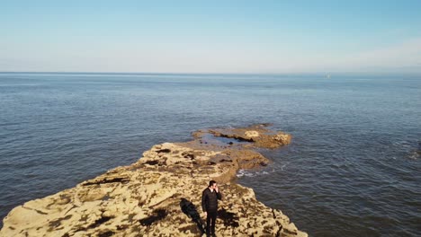 toma de seguimiento de drones de 4k del sujeto caminando hacia la cámara, a lo largo de la costa rocosa