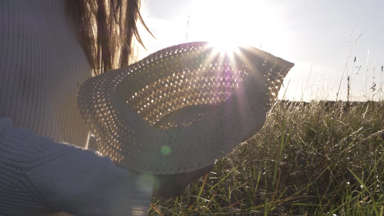 Woman using straw hat as fan in summer background medium shot