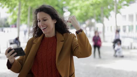 mujer joven alegre usando un teléfono inteligente al aire libre