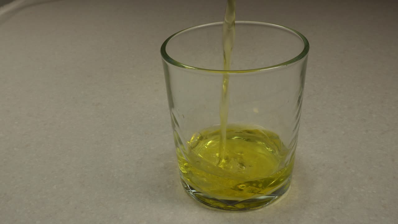 노란색 액체가 작은 컵에 부어집니다.
