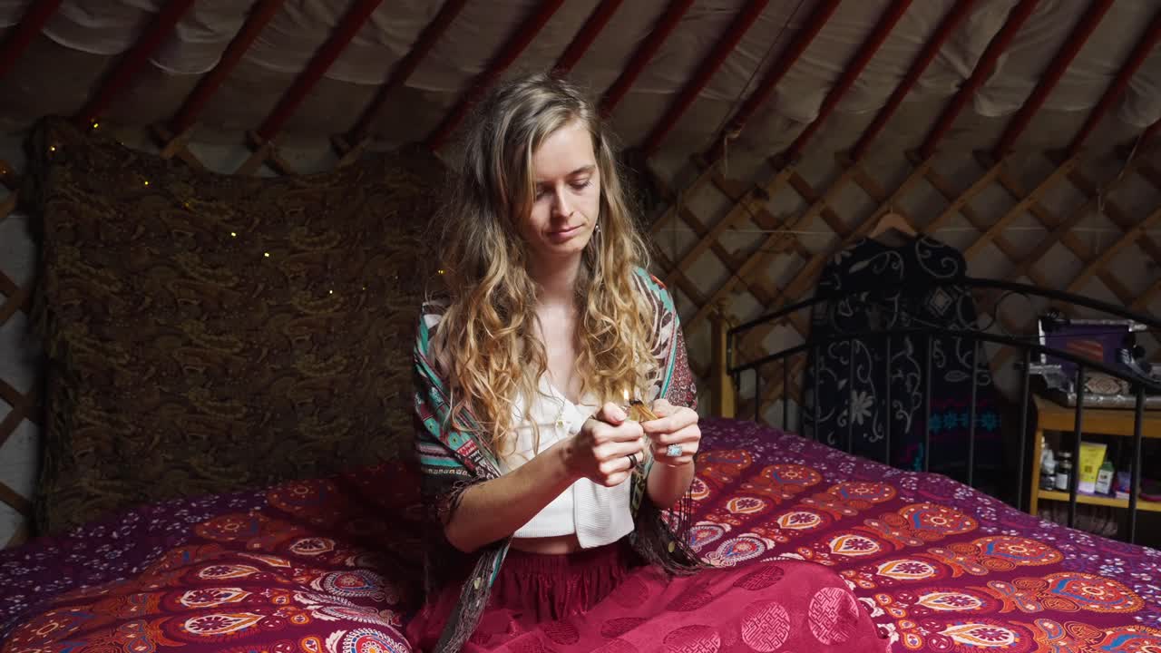 mujer espiritual consciente del medio ambiente en la cama encendiendo incienso, palo santo