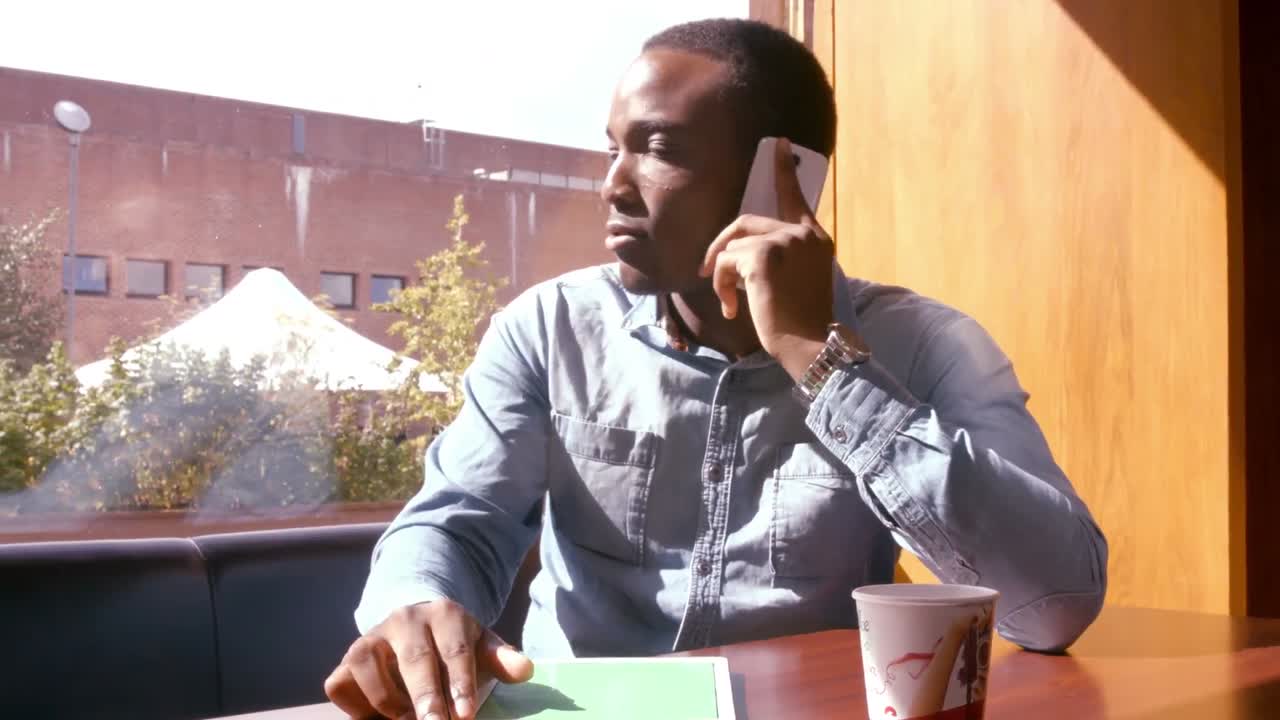 Handsome man using tablet and having a phone call