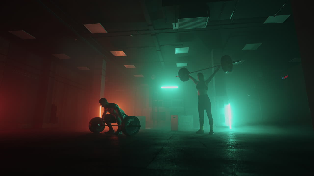 A man and a woman in a colored neon red and blue light in slow motion lift heavy barbells over their heads. Strength and power training with heavy weight. The concept of athletic and strong couples