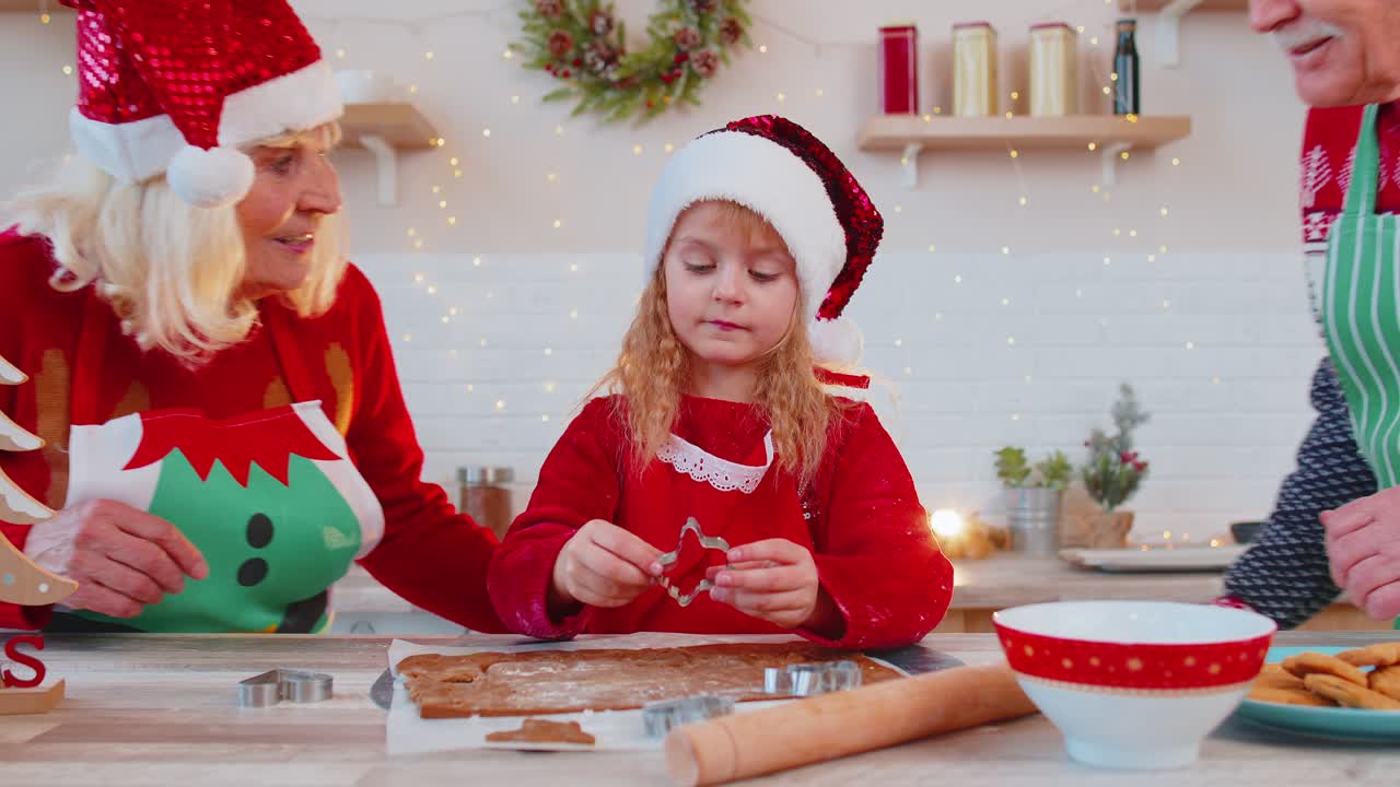 abuelos mayores con nieta niña preparando, cocinando galletas en casa cocina navideña