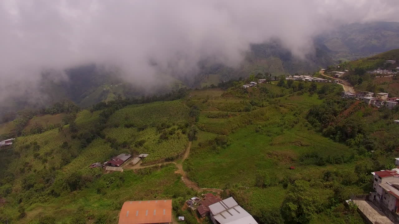 Drone che segue strade sterrate dirette verso montagne nebbiose.