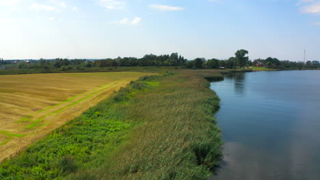 Aerial-view-of-drone-flying-above-farmland-river-in-the-background