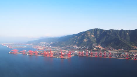 Vista-De-Pájaro-Del-Barco-De-Transporte-De-Contenedores-De-Carga-Y-Grúa-En-El-Distrito-Industrial-Del-Puerto-Marítimo,-Silueta-Puesta-De-Sol