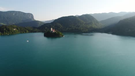 Iglesia-En-La-Pequeña-Isla-Del-Lago-Bled-Eslovenia-Asombrosa-Bahía-Escénica-Natural-Turquesa-Aguas-Tranquilas,-Vista-Aérea-De-Drones,-Viaje-Destino-Europeo