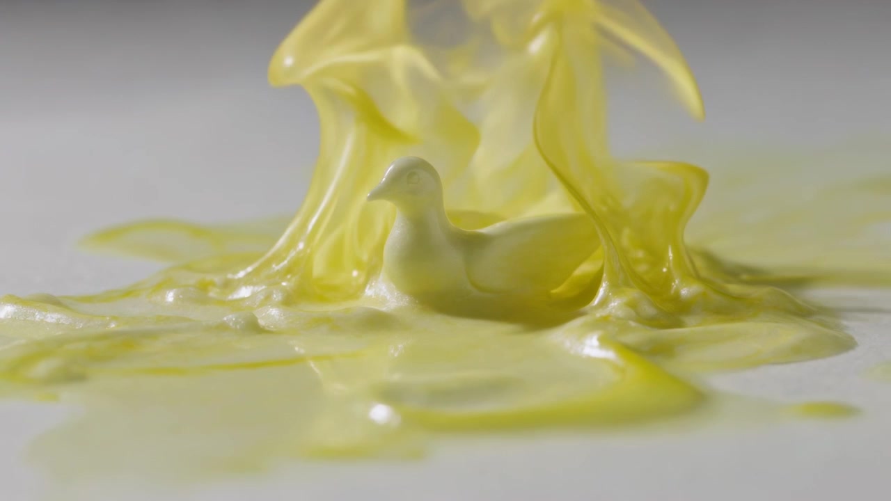 Impacting studio tabletop, thick yellow liquid forming arching sheets around small duck figurine
