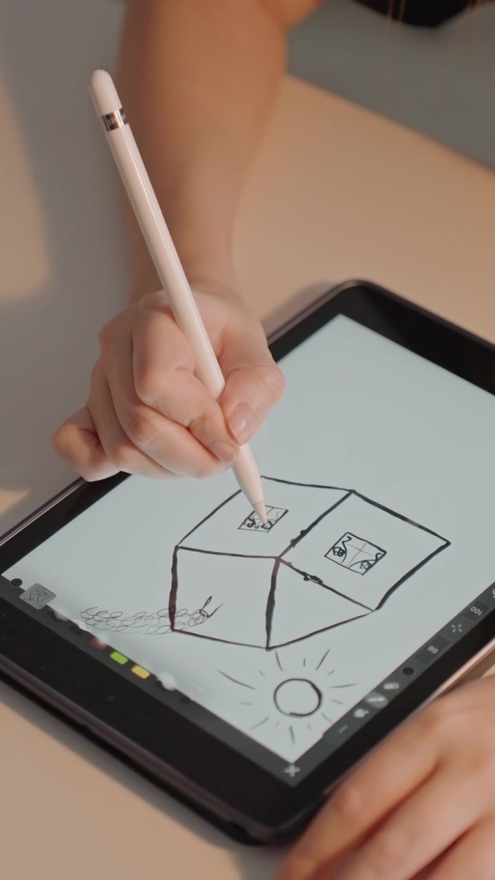 Jovem mulher desenha formas geométricas em um tablet com um Apple Pencil. O desenho apresenta cubos com faces dentro de quadrados em cada cubo. Seu cabelo castanho comprido é parcialmente visível enquanto a mulher se concentra.