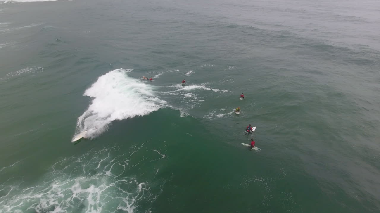 cinemática de acción aérea sobrevolando a los surfistas surfeando en coffee bay en sudáfrica
