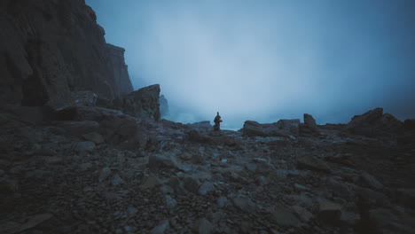 mysterious figure stands among rocky terrain during foggy twilight hours