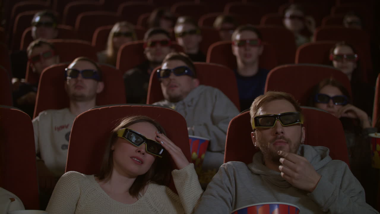 3d 안경을 입은 관객들이 무서운 영화를 보며 긴장하고 있습니다. 3d 영화관의 관객