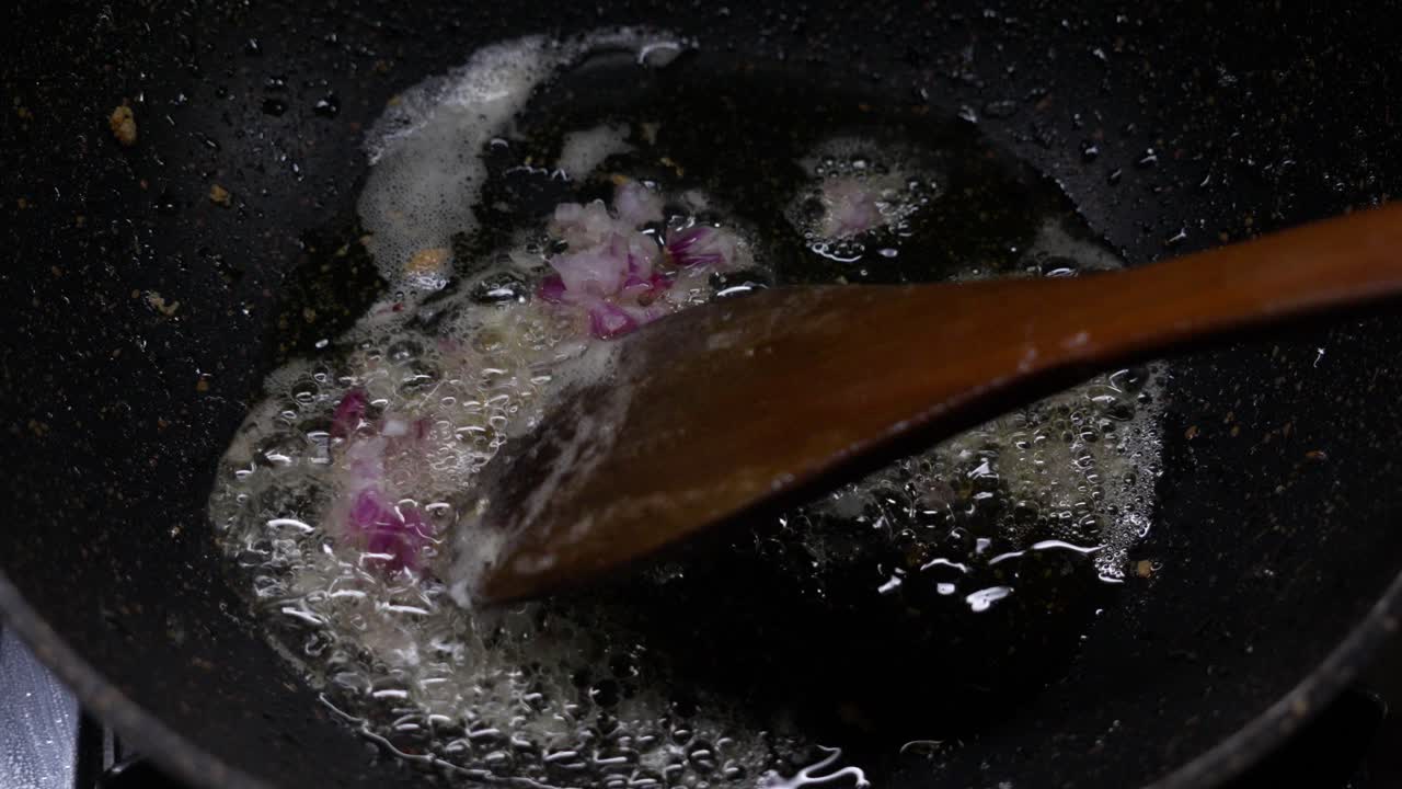 Close Shot Frying Pan with Boiling Oil as Cook Adds Red Onion and Stirs