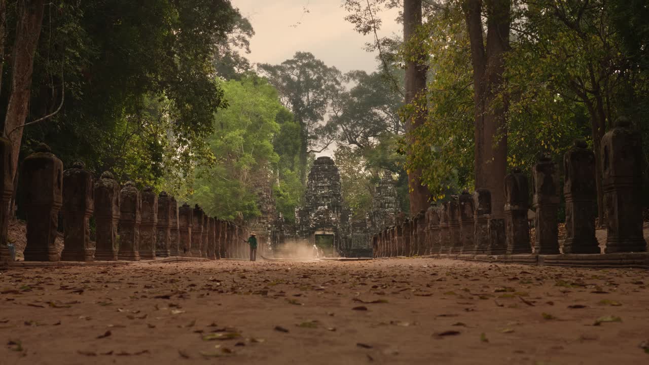 Femme dépoussiérant une allée devant l'entrée d'un temple à Angkor, Cambodge. 4K.