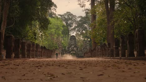 woman dusting of a pathway in front of an entrance to a temple in angkor, cambodia. 4k