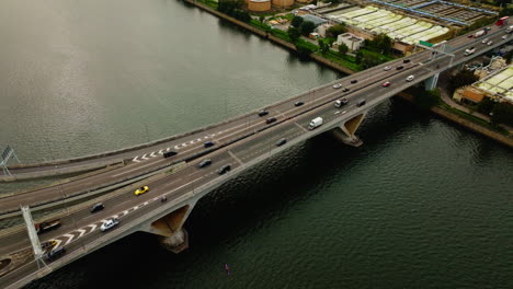 drone shot of traffic cars driving on highway over a wide waterway bridge, china