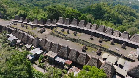 a smooth aerial shot of a small village and a large green forest in indonesia