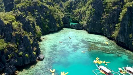 low flying aerial of boats and kayaks at entrance to big lagoon, small lagoon, el nido, palawan, philippines