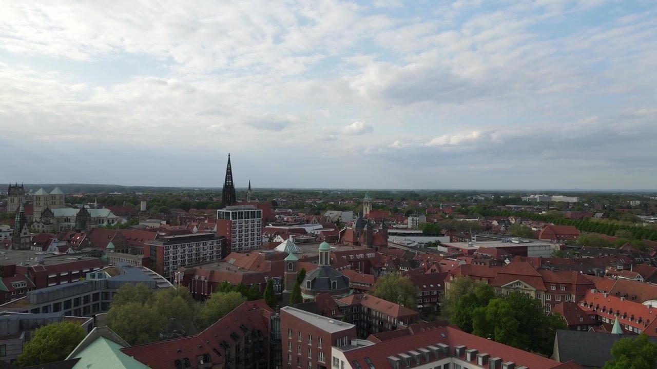 Drone che sorvola in un ampio cerchio la cattedrale di Münster e i tetti storici circostanti alla luce della sera