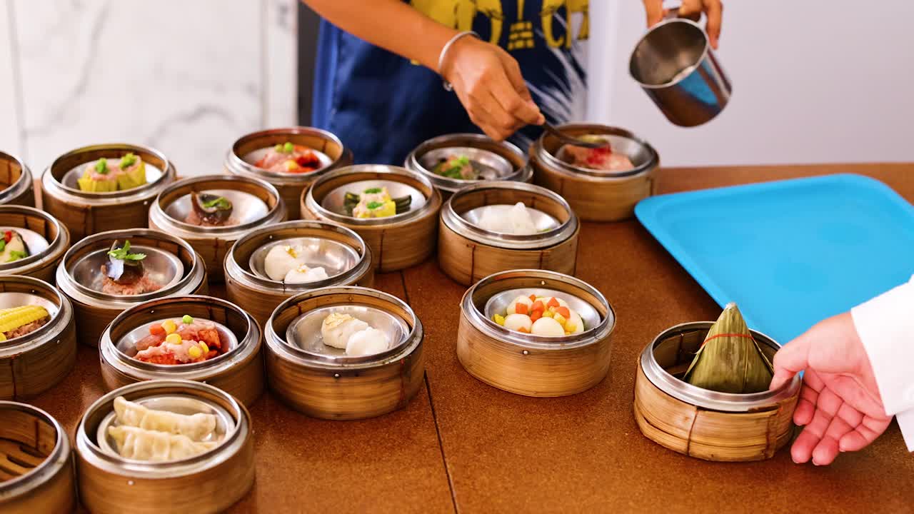 A vendor arranges and serves dim sum in bamboo steamers at a bustling market in Phuket, Thailand. Bright, lively atmosphere