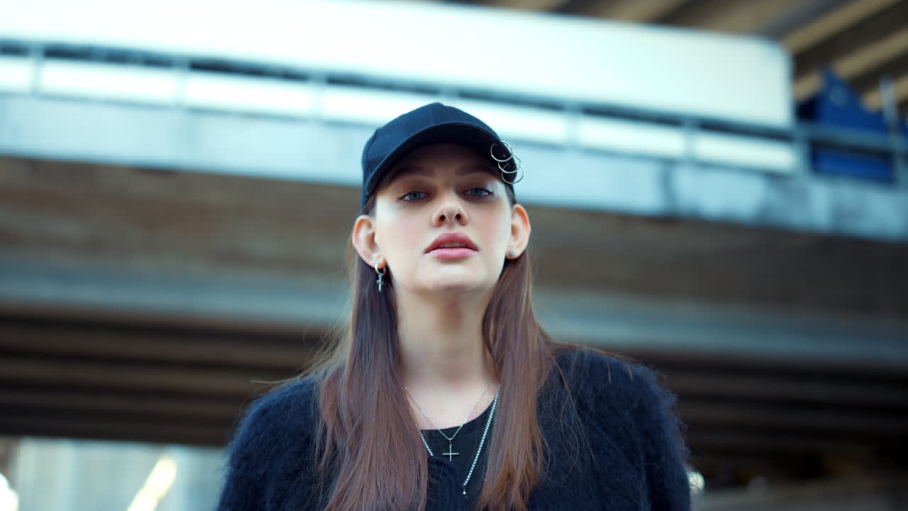 Stylish girl looking at camera on urban street. Serious woman posing at street