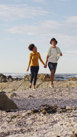 una pareja biracial disfruta de un paseo por la playa, con espacio para copiar