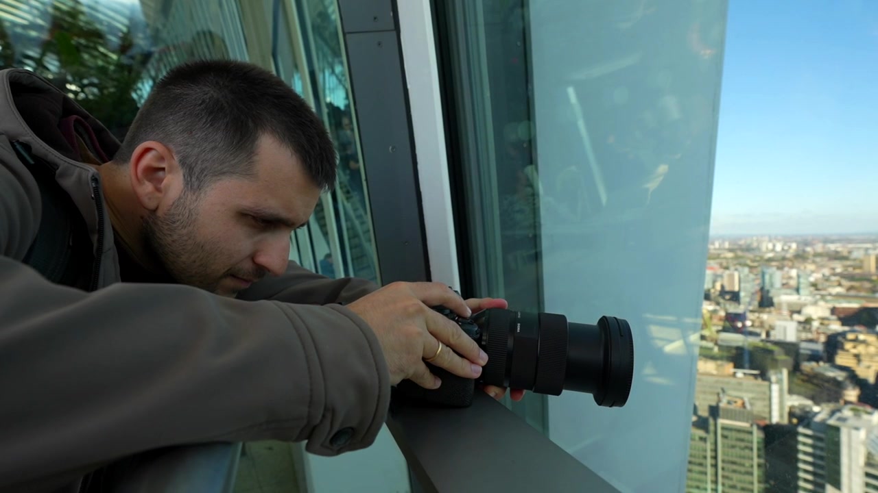 Fotografo che cerca di scattare una bella foto da un grattacielo attraverso una finestra.