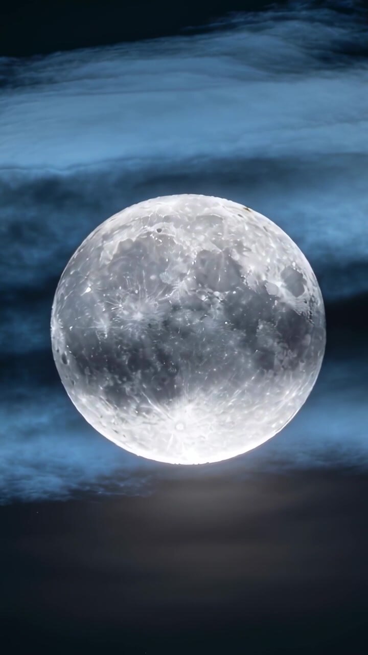 Vídeo vertical: Lua cheia brilhante permanecendo centralizada no céu noturno, com nuvens finas flutuando e velando a borda.