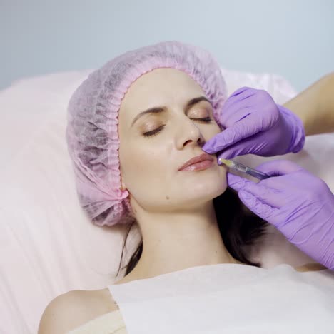 a beautiful woman is lying on a couch at a reception by a beautician. the doctor makes beauty injections to the lips.